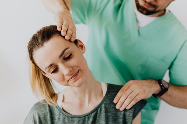 Physiotherapist treating patient's jaw and neck for TMJ dysfunction relief